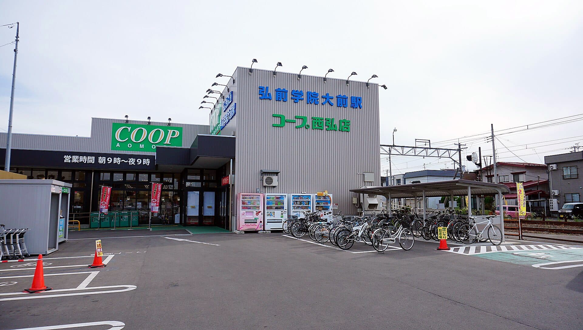 A blue COOP consumer cooperative supermarket beside a railway station in Hirosaki, Japan